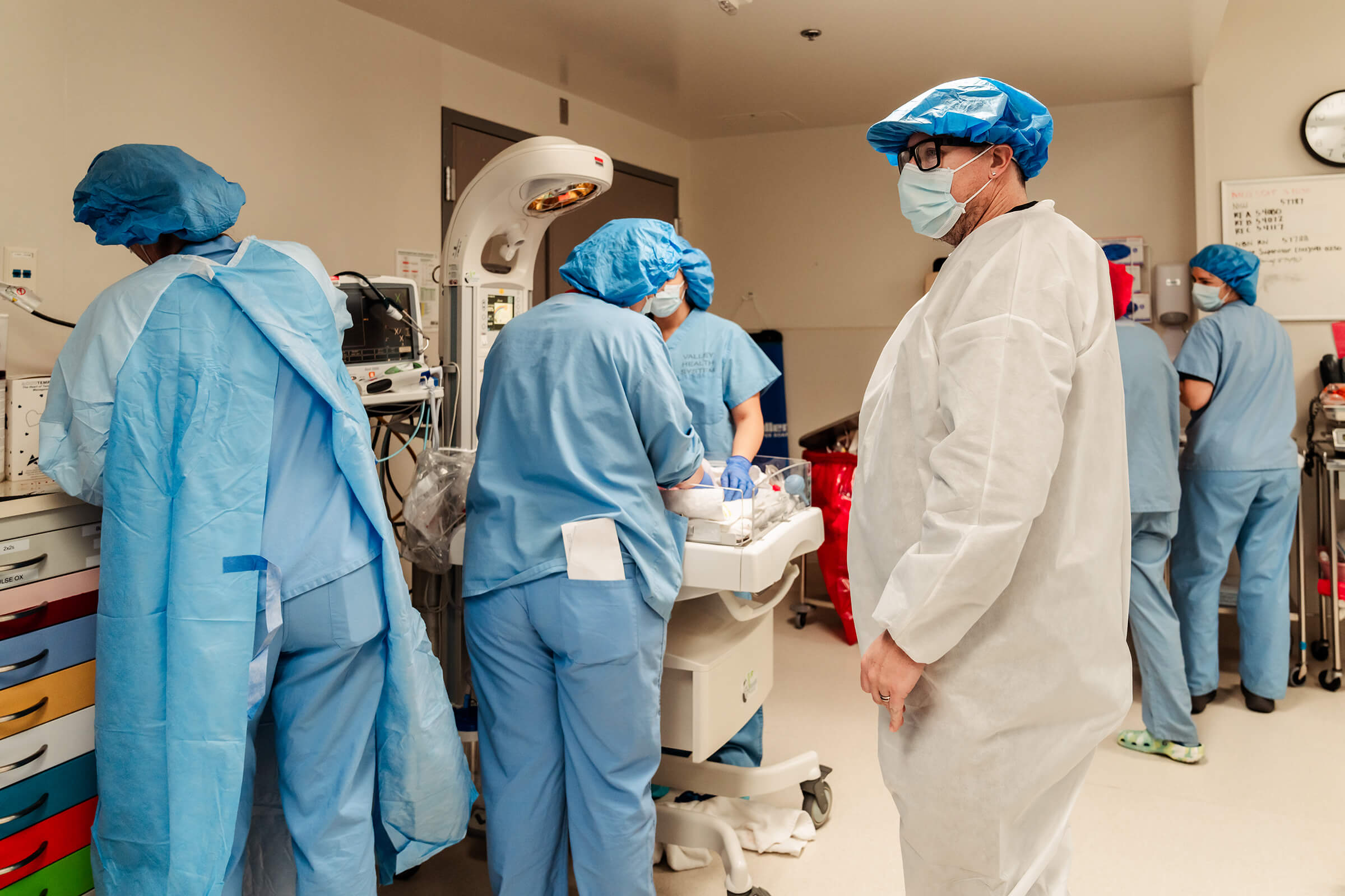 father standing alongside team in the operating room as they assess his twin girls