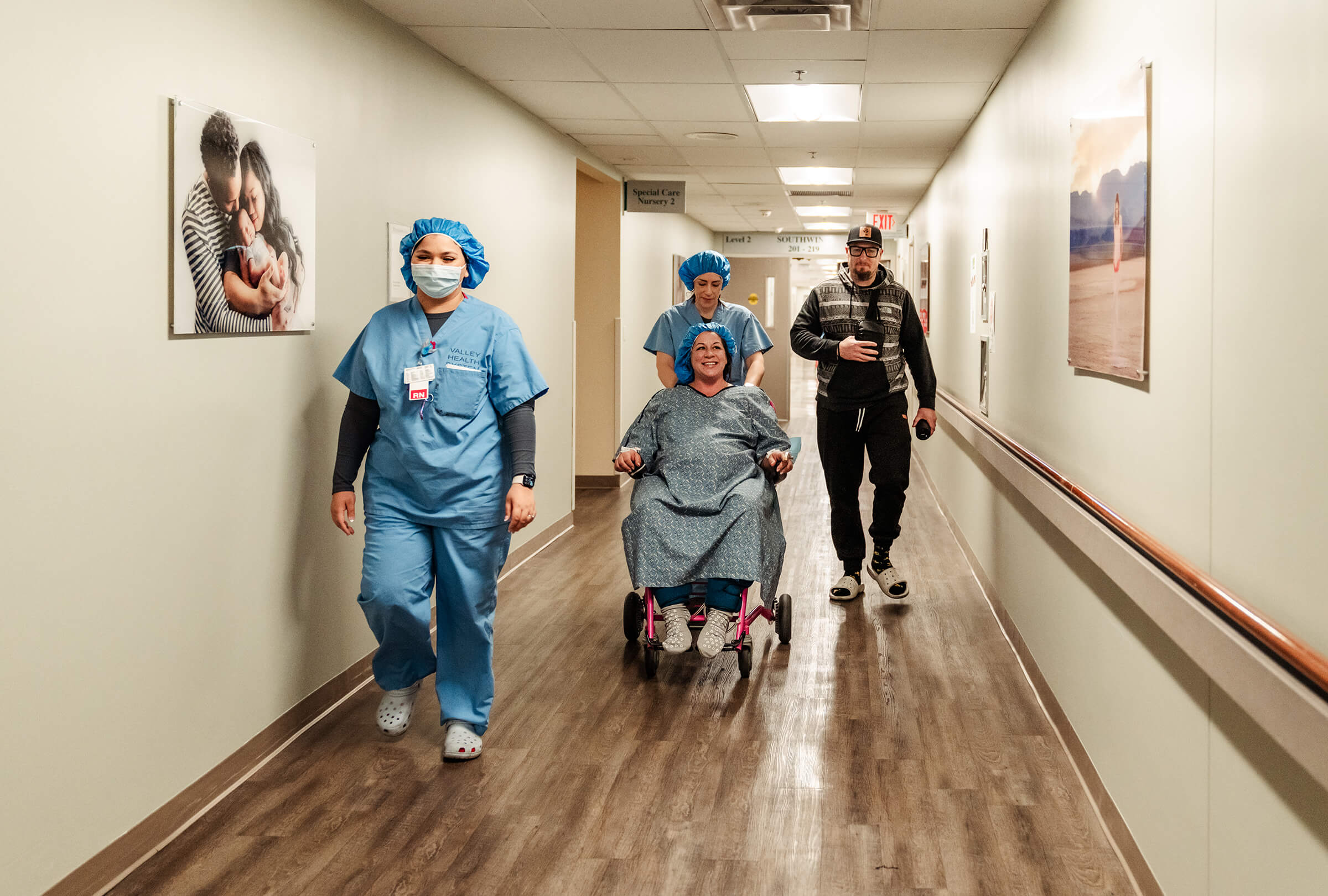 two nurses accompany a patient in a wheelchair as she's taken to the operating room for a c-section