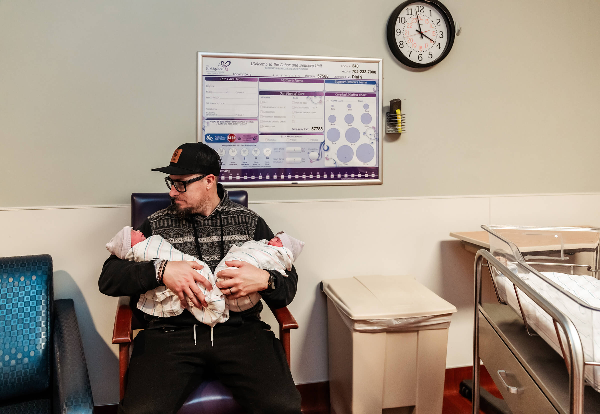 Father holding his twins in the recovery room as he awaits mom