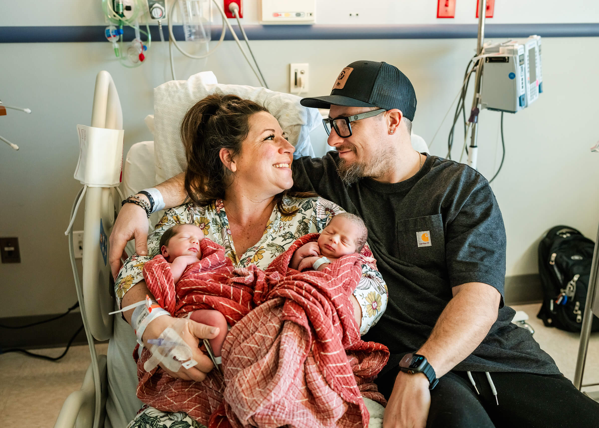 proud parents holding their twin girls in the hospital